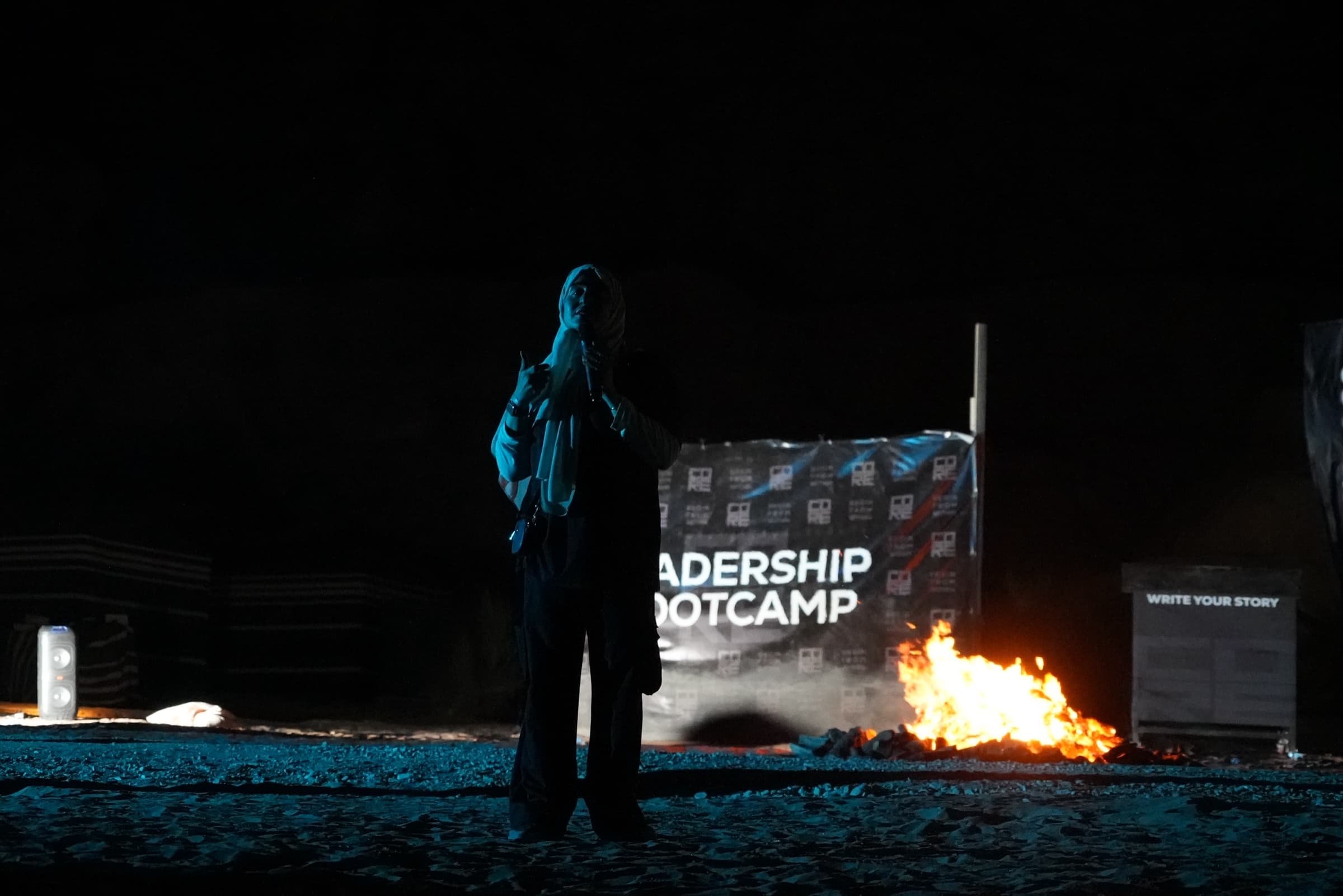 A CORE facilitator leading a night leadership session beside a fire