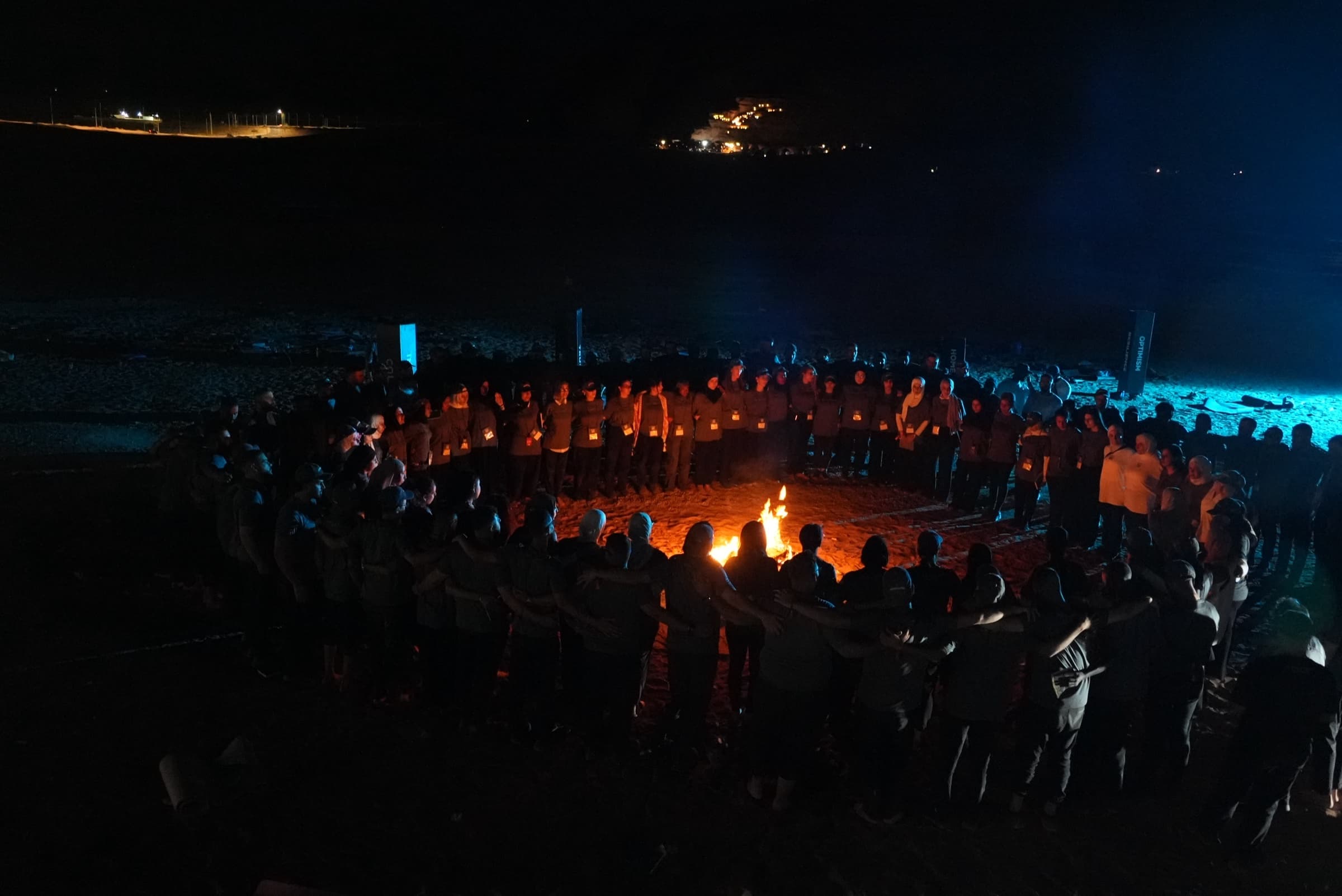 Leadership retreat participants linked together around a fire at night